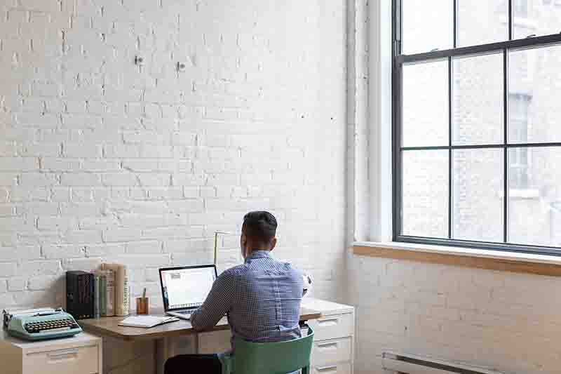 Enterpeneur seen from behind using a laptop to manage his ecommerce business